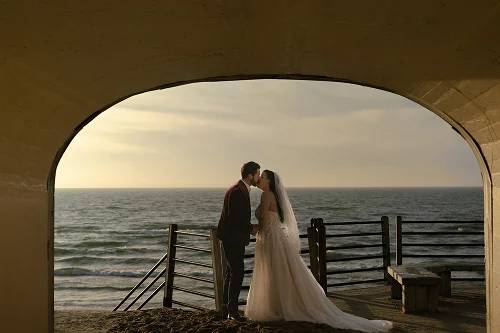 A newly wed couple kissing in a tunnel.